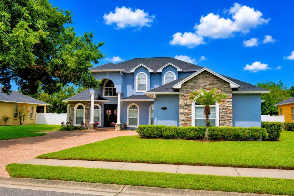 A two-story blue house with a stone facade, arched windows, and a paved driveway — 5516 BLACK HAWK LANE, LAKELAND, FL