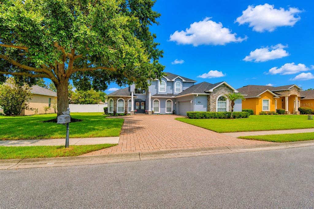 A two-story house with a brick driveway, stone accents, and a large tree in front — 5516 BLACK HAWK LANE, LAKELAND, FL