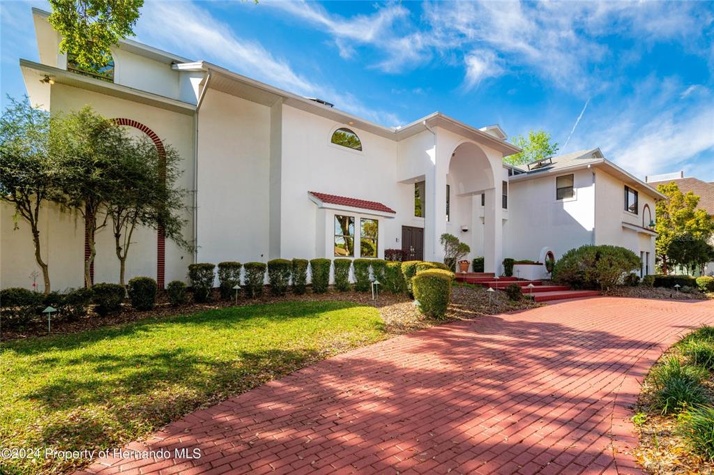 A large white house with a red brick driveway and a red-tiled roof section — 11915 W RIVERHAVEN DRIVE, HOMOSASSA, FL