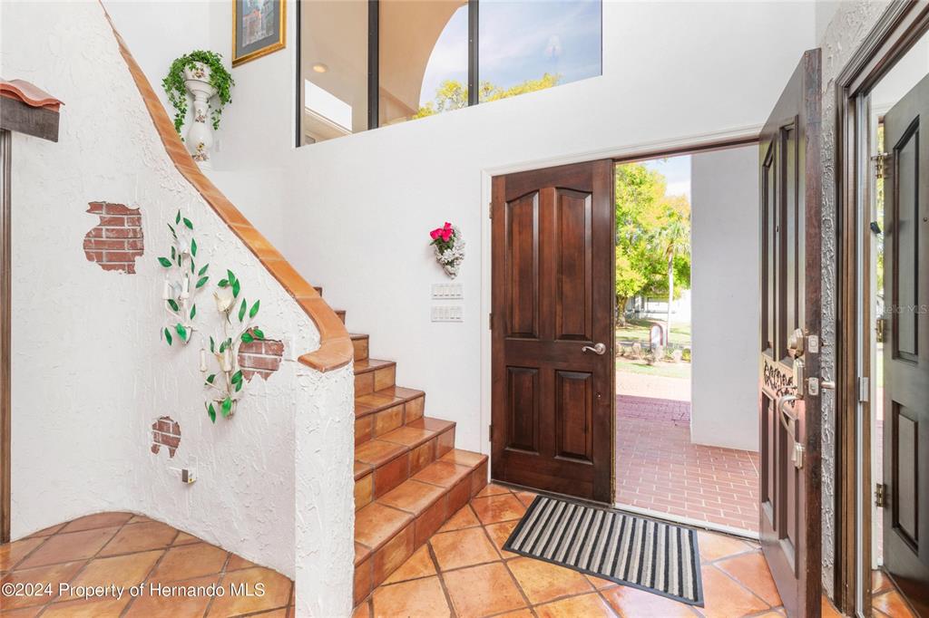 An entryway features a tiled staircase, a dark wood door, and white textured walls — 11915 W RIVERHAVEN DRIVE, HOMOSASSA, FL