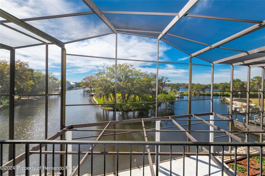 A screened-in balcony overlooks a canal and a small island with trees — 11915 W RIVERHAVEN DRIVE, HOMOSASSA, FL