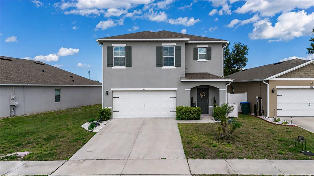 A two-story gray house with a white garage door and a small front porch — 928 AUGUST SKY DRIVE, DELTONA, FL
