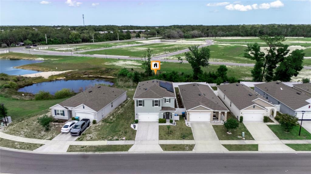 An aerial view shows a row of suburban houses with driveways and a nearby pond — 928 AUGUST SKY DRIVE, DELTONA, FL