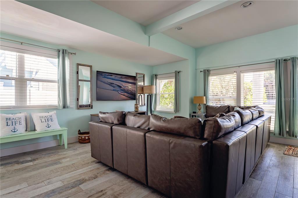 A living room features a large brown sectional sofa, light blue walls, and wood-look flooring — 504 SPRING AVENUE, ANNA MARIA, FL