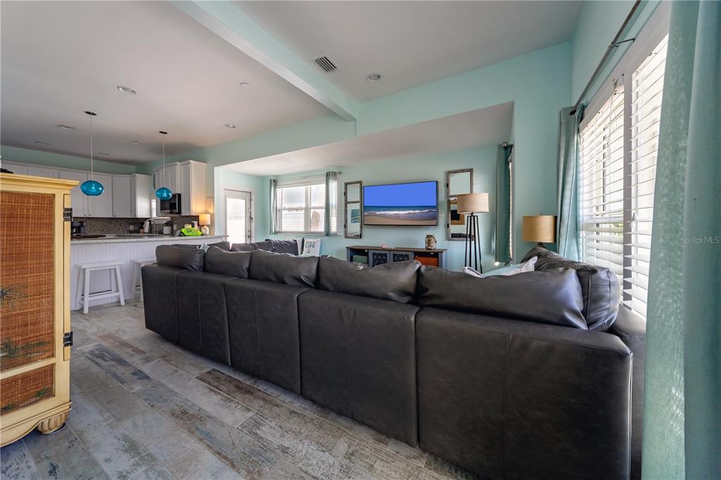 A living room features a large dark sectional sofa, light blue walls, and wood-look tile flooring — 504 SPRING AVENUE, ANNA MARIA, FL