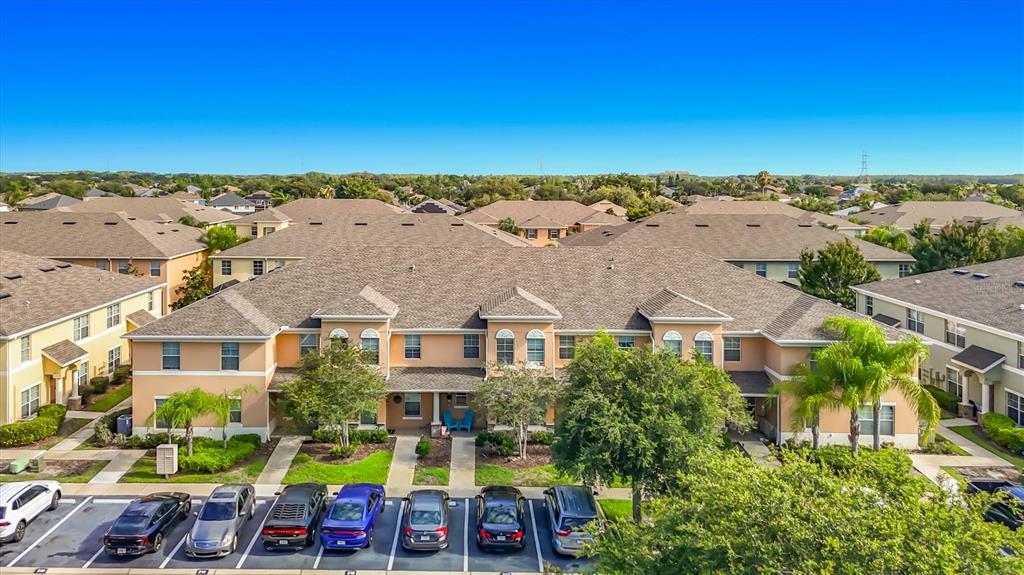 An aerial view shows a multi-unit residential building with a parking lot in front — 9838 TRUMPET VINE LOOP, TRINITY, FL