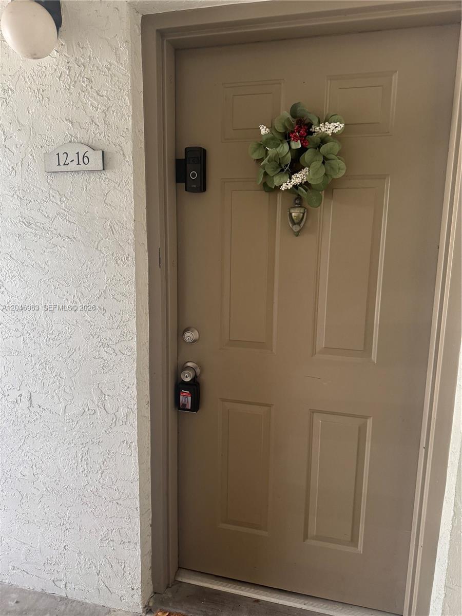 A tan exterior door features a wreath, a smart doorbell, and a lockbox on the handle — 520 S Park Rd # 12, Hollywood FL 33021, HOLLYWOOD, FL