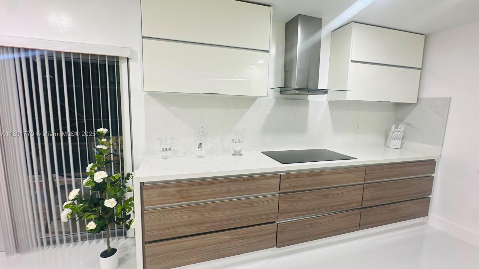 A modern kitchen features white upper cabinets, wood-grain lower drawers, and a stainless steel hood — 541 SE 17th Ave # 541, Deerfield Beach FL 33441, DEERFIELD BEACH, FL