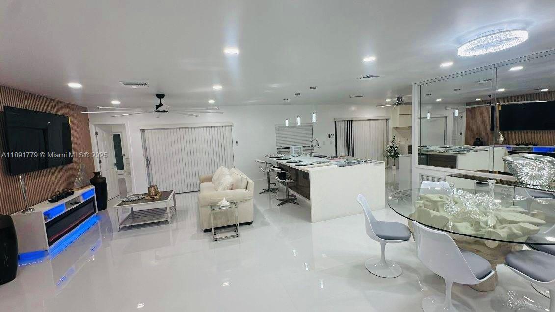 This open-concept living and dining area features white tile floors, a kitchen island, and recessed lighting — 541 SE 17th Ave # 541, Deerfield Beach FL 33441, DEERFIELD BEACH, FL