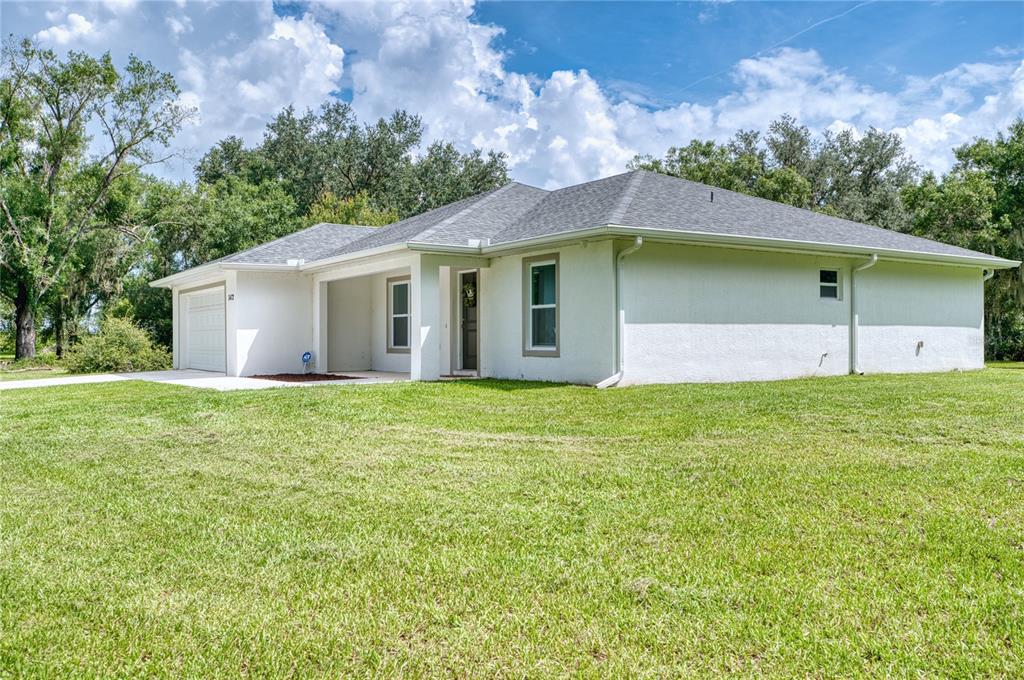 A single-story white stucco house with a gray shingled roof and a two-car garage — 3472 NE DAVIS STREET, ARCADIA, FL