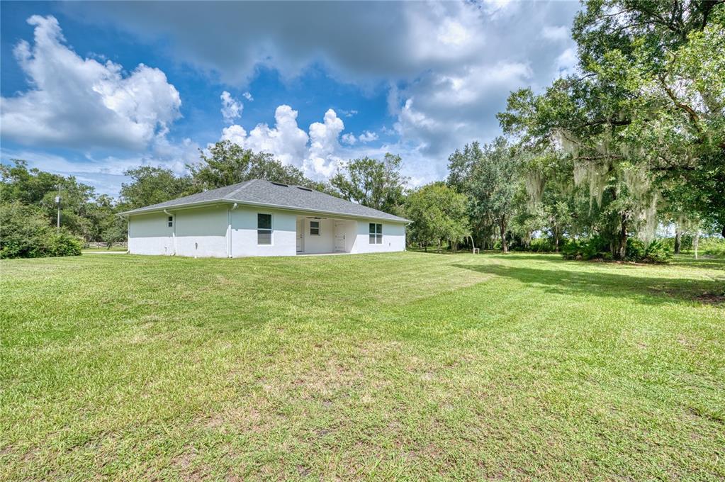 A white, single-story house with a gray roof sits on a large, grassy lawn — 3472 NE DAVIS STREET, ARCADIA, FL
