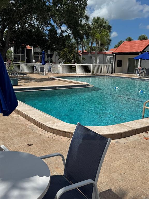 A swimming pool with a stone deck and patio furniture sits outside a building — 3217 BENEVA ROAD UNIT 202, SARASOTA, FL