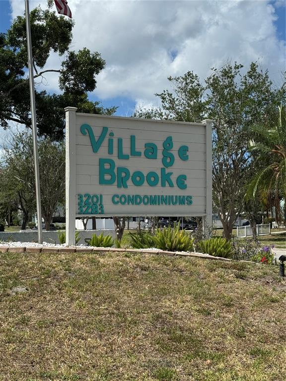 A sign for Village Brooke Condominiums stands in a grassy area with trees behind it — 3217 BENEVA ROAD UNIT 202, SARASOTA, FL
