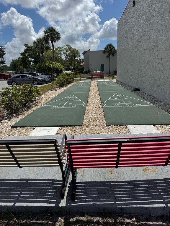 Two outdoor shuffleboard courts are situated next to a building wall with benches in front — 3217 BENEVA ROAD UNIT 202, SARASOTA, FL