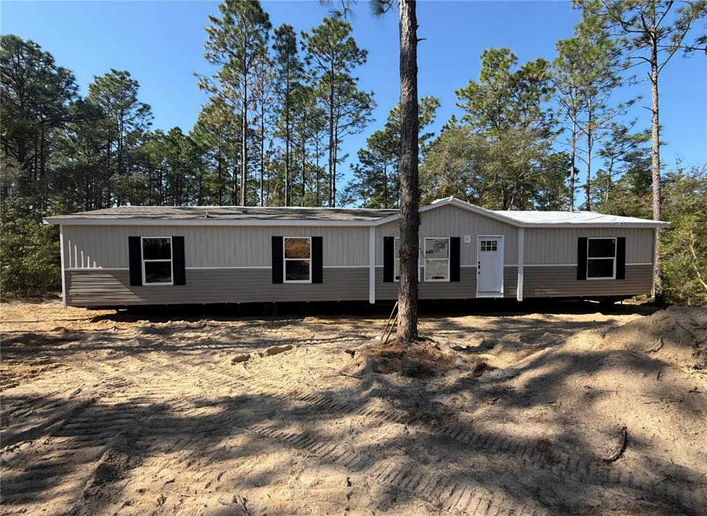 A single-story manufactured home with two-tone siding sits on a cleared, sandy lot — 4165 SW 168TH CIRCLE, OCALA, FL