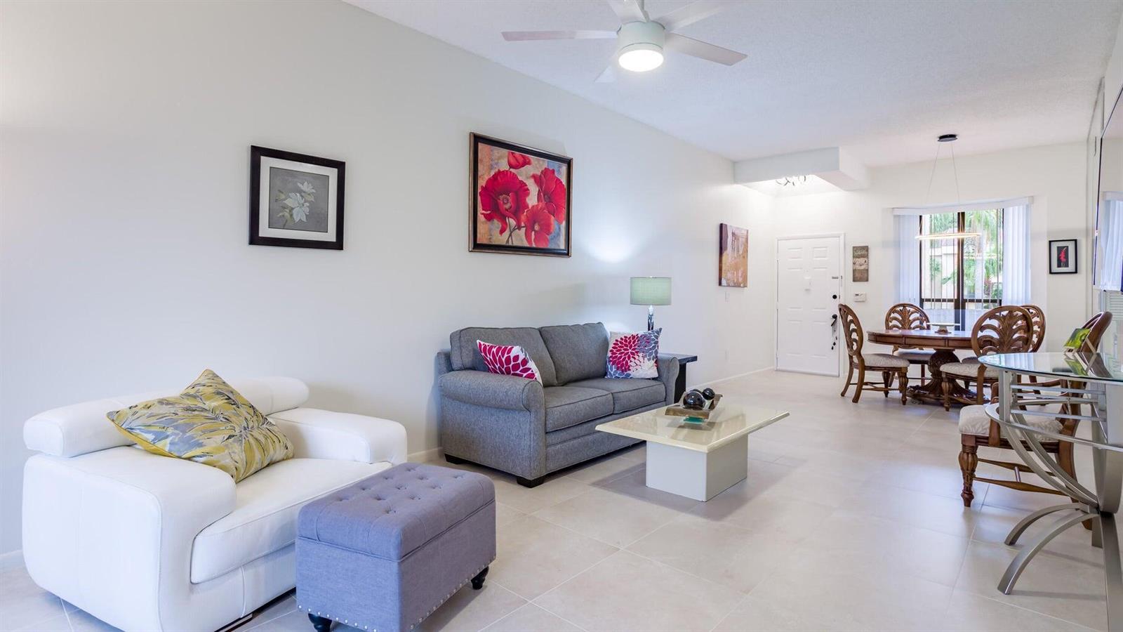 A living room with a white armchair, gray sofa, coffee table, and adjacent dining area — 7460 La Paz Boulevard # 208, Boca Raton FL 33433, BOCA RATON, FL