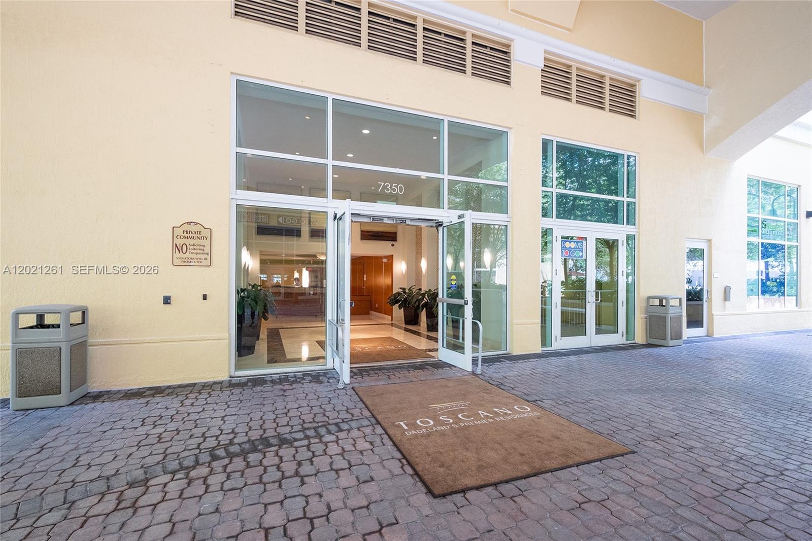 The exterior entrance of a residential building features glass double doors and a paved walkway — 7350 SW 89th St # 1410S, Miami FL 33156, MIAMI, FL