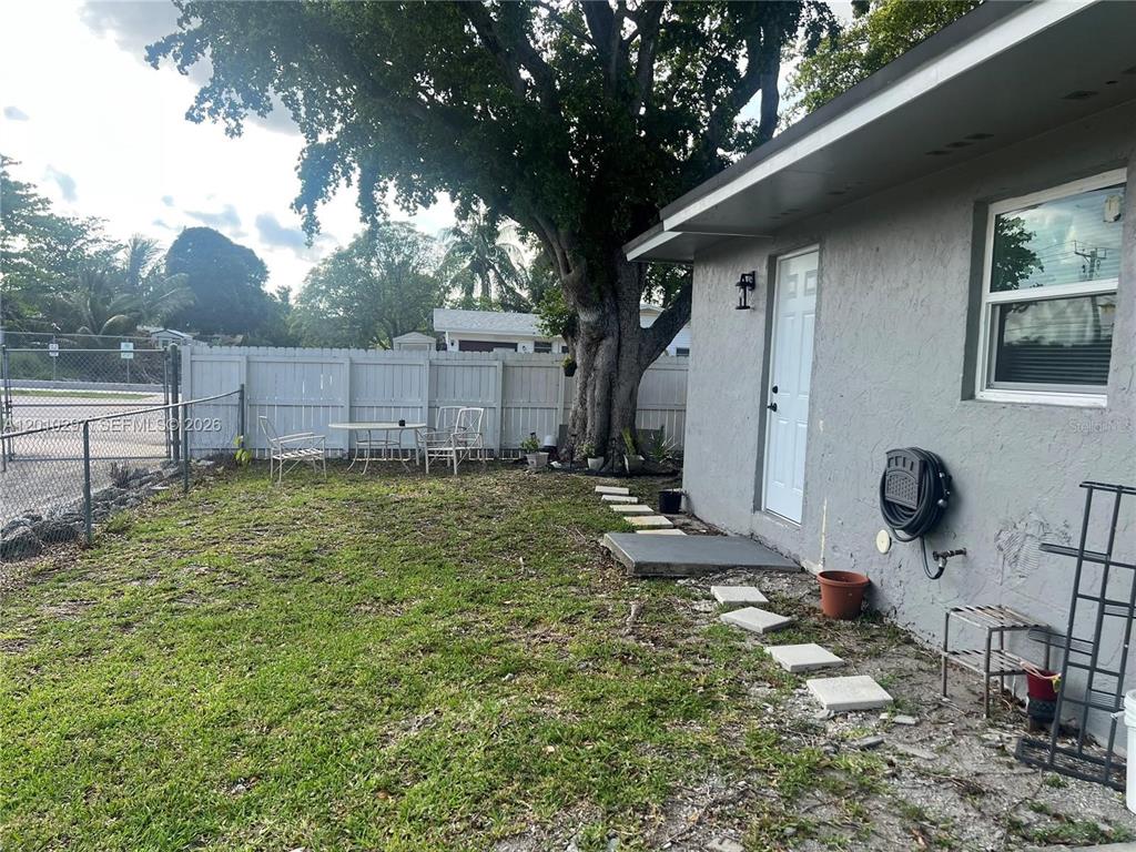 A gray house exterior features a white door, a window, and a backyard with trees — 6742 SW 18 COURT UNIT 2, NORTH LAUDERDALE, FL