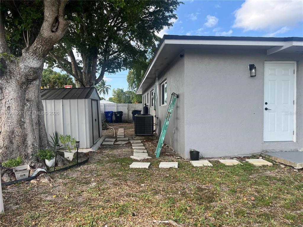 The exterior of a gray house features a white door, a metal shed, and a ladder — 6742 SW 18 COURT UNIT 2, NORTH LAUDERDALE, FL