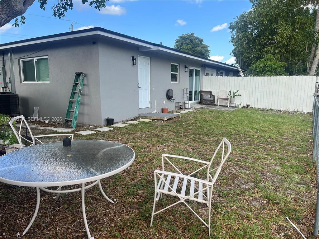A backyard features a gray house exterior, a glass-topped table, and white metal chairs — 6742 SW 18 COURT UNIT 2, NORTH LAUDERDALE, FL