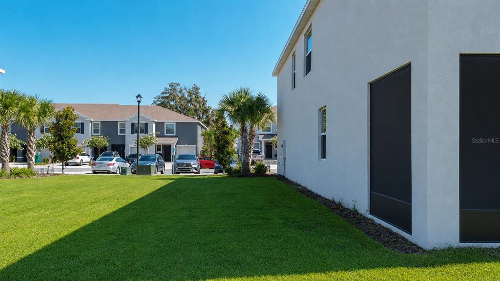 A side view of a white house exterior with a grassy lawn and parked cars — 5311 DRAGONFLY DRIVE, WILDWOOD, FL