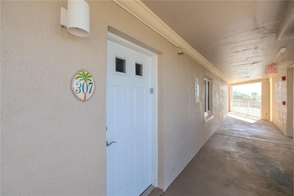 An exterior hallway features a white door labeled 307 with a palm tree sign — 5501 S ATLANTIC AVENUE UNIT 3070, NEW SMYRNA BEACH, FL