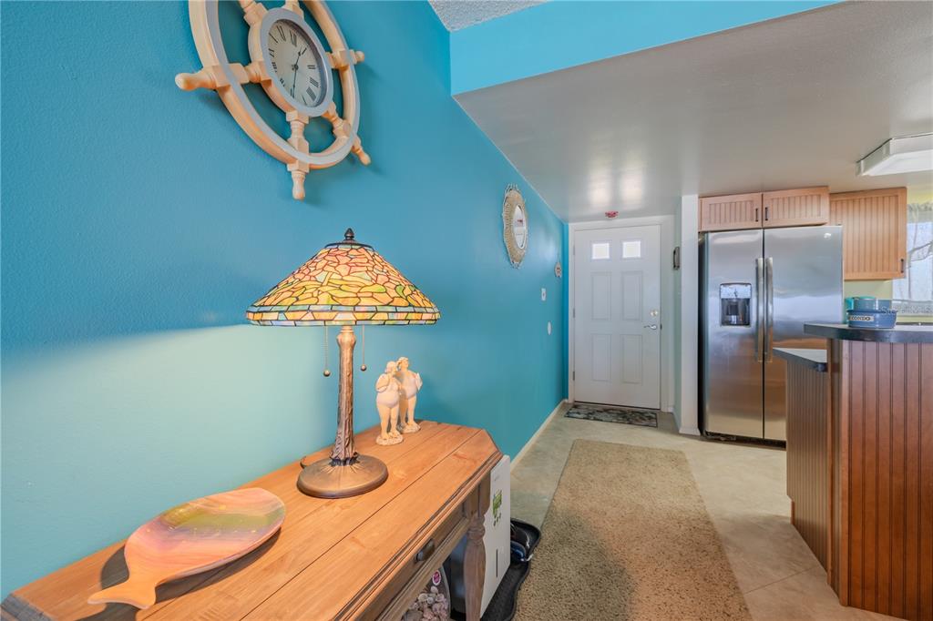 A hallway with a blue wall, a wooden console table, a lamp, and a front door — 5501 S ATLANTIC AVENUE UNIT 3070, NEW SMYRNA BEACH, FL