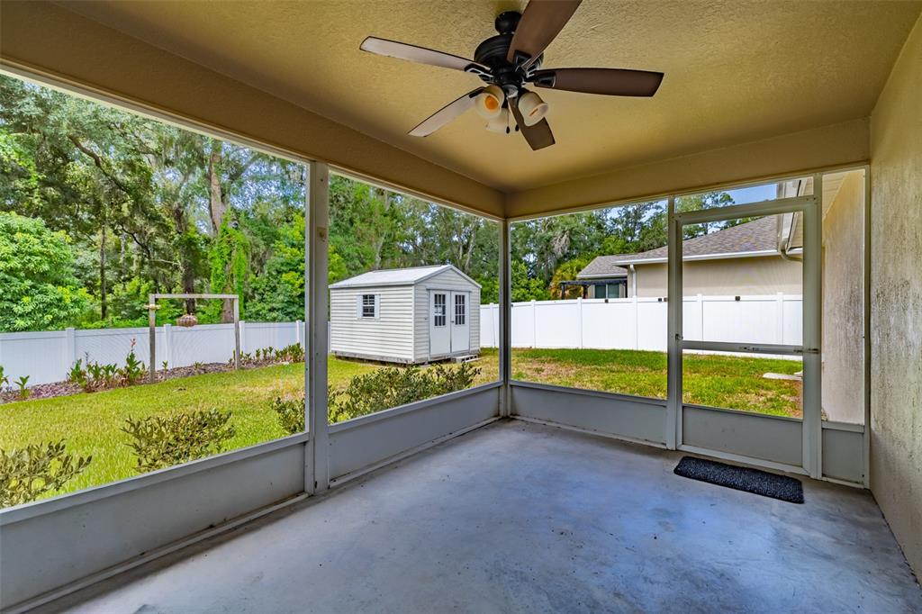 A screened-in patio with a ceiling fan overlooks a fenced backyard with a storage shed — 1746 GREY FOX DRIVE, LAKELAND, FL