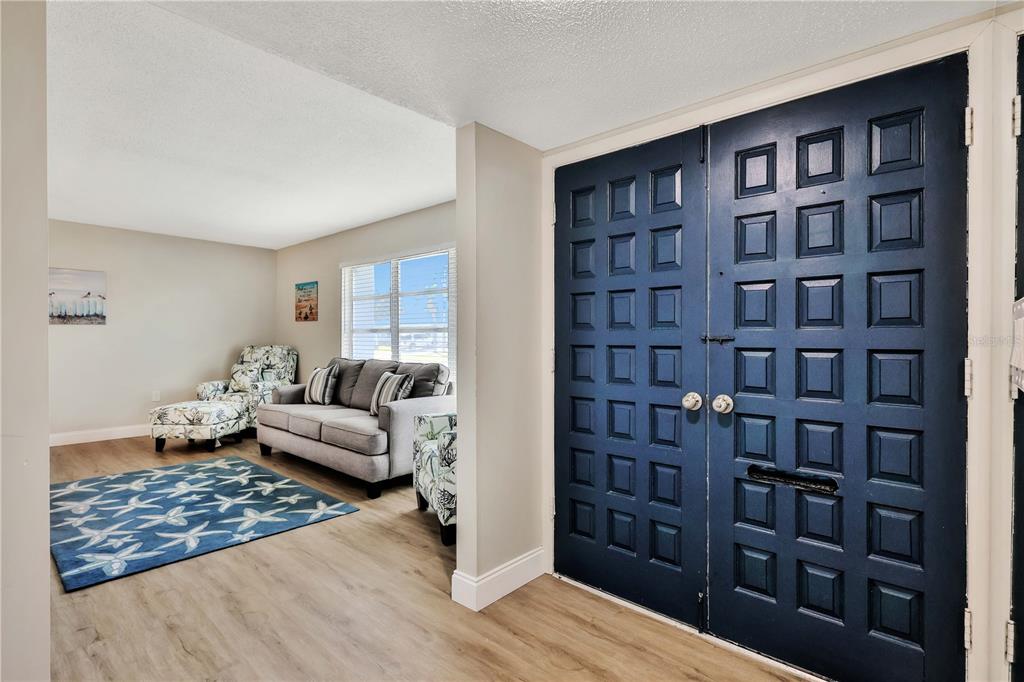 An entryway with wood-look flooring leads to a living area with a sofa and rug — 6462 OTIS ROAD, NORTH PORT, FL