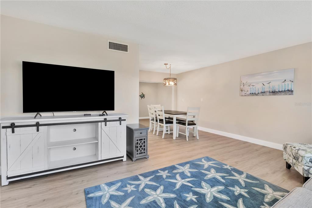 A living and dining area with light wood floors, a white media console, and a rug — 6462 OTIS ROAD, NORTH PORT, FL