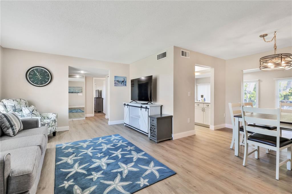 A living room with light wood flooring, a blue starfish rug, and a dining area — 6462 OTIS ROAD, NORTH PORT, FL