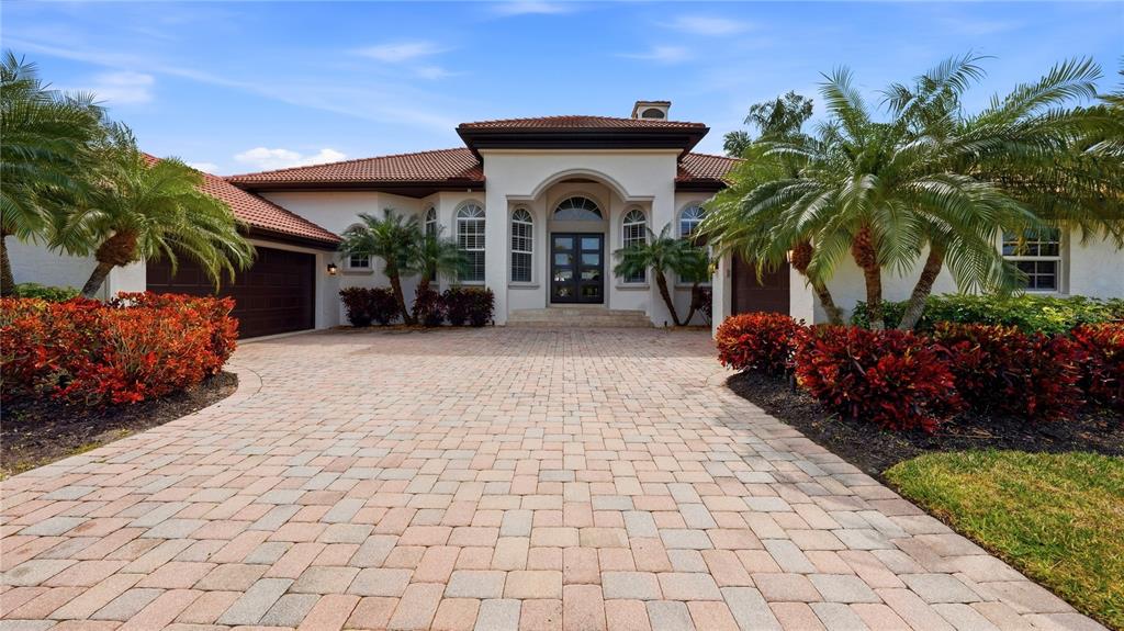 A single-story house with a paved driveway, palm trees, and a dark-framed front entrance — 7637 COVE TERRACE, SARASOTA, FL