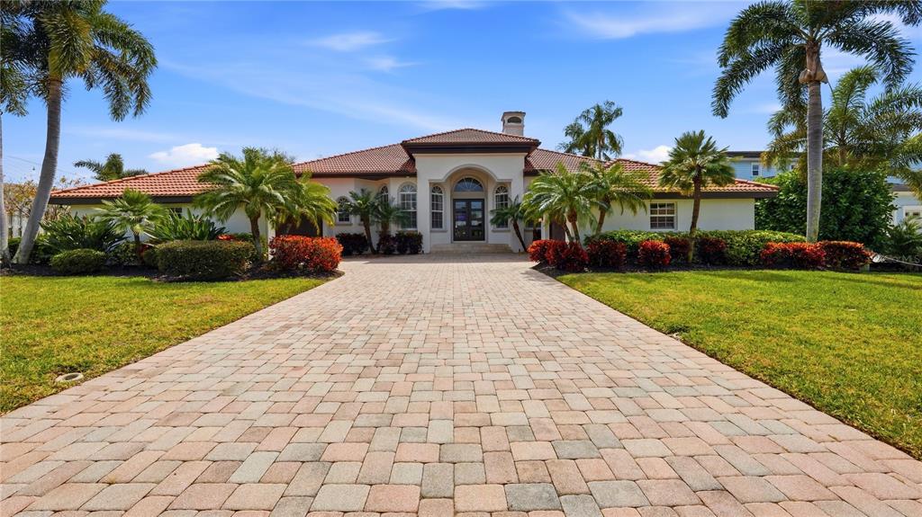 A single-story house with a tiled roof, arched entryway, and a paved driveway — 7637 COVE TERRACE, SARASOTA, FL