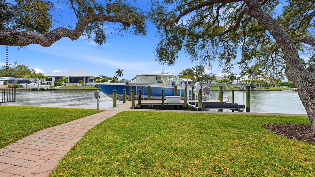 A blue boat is docked at a pier on a canal near a grassy lawn — 7637 COVE TERRACE, SARASOTA, FL