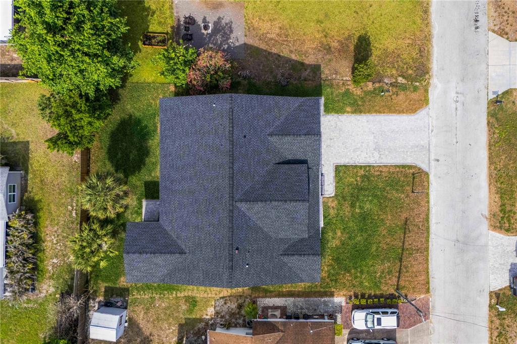 An aerial view shows a house with a gray shingled roof and a paved driveway — 8526 INDIES DRIVE, HUDSON, FL