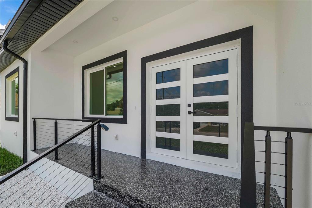A modern white exterior entrance features double glass doors, a window, and black metal railings — 8526 INDIES DRIVE, HUDSON, FL