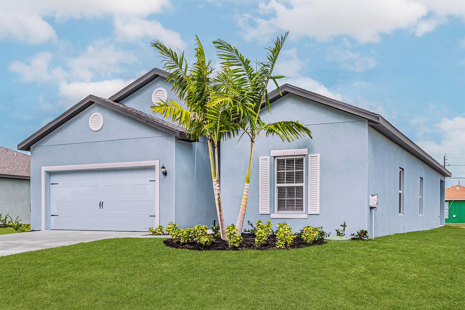 A light blue single-story house with a two-car garage, palm tree, and manicured lawn — 7885 103rd Court, Vero Beach FL 32967, VERO BEACH, FL