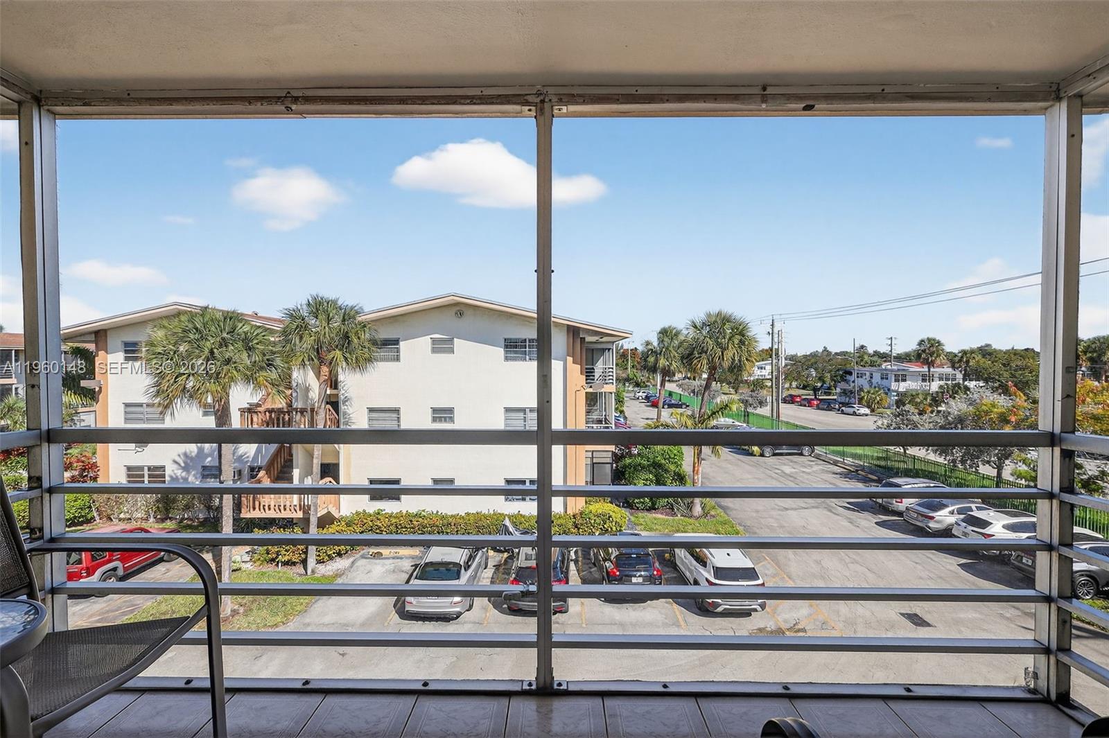 A view from a screened balcony overlooking a parking lot and a neighboring apartment building — 16900 NE 14th Ave # 302, Miami FL 33162, MIAMI, FL