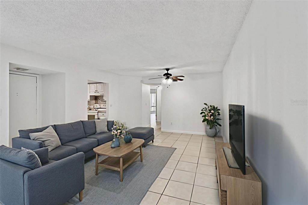 A living room features a blue sectional sofa, a wooden coffee table, and tile flooring — 4369 AQUA VISTA DRIVE UNIT 16-C, ORLANDO, FL