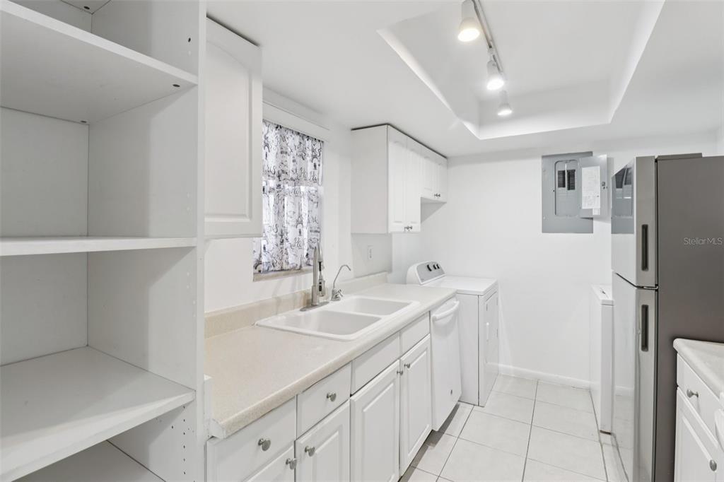 A white kitchen features a double sink, laundry appliances, and a stainless steel refrigerator — 4369 AQUA VISTA DRIVE UNIT 16-C, ORLANDO, FL
