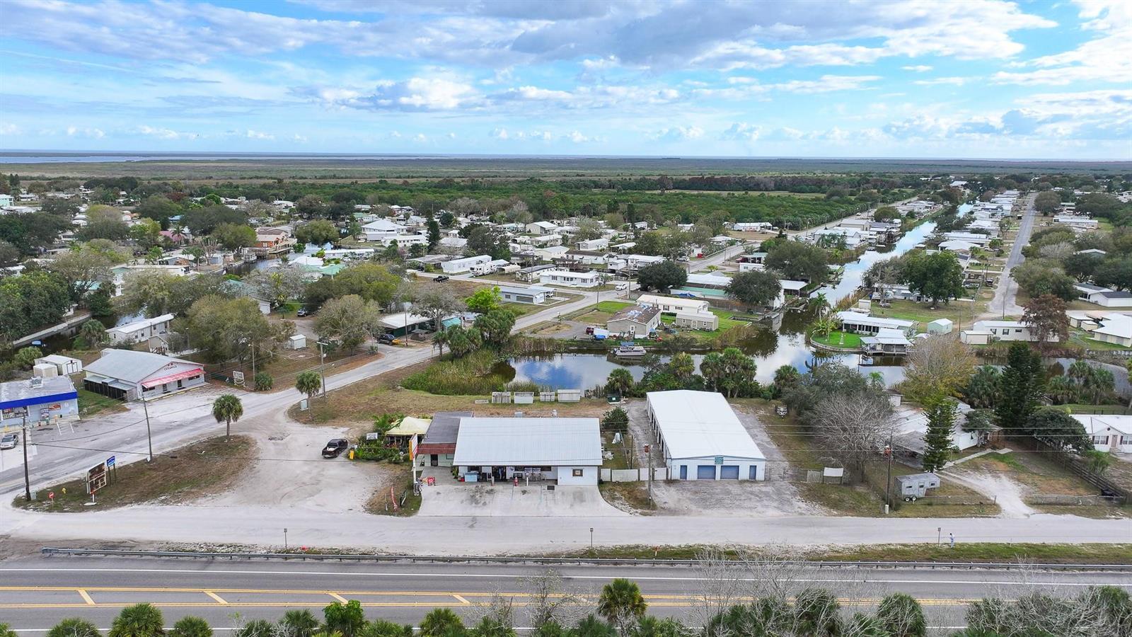 An aerial view shows a commercial building and storage units near a canal-side residential neighborhood — 1110 Buckhead Ridge Road, Okeechobee FL 34974, OKEECHOBEE, FL