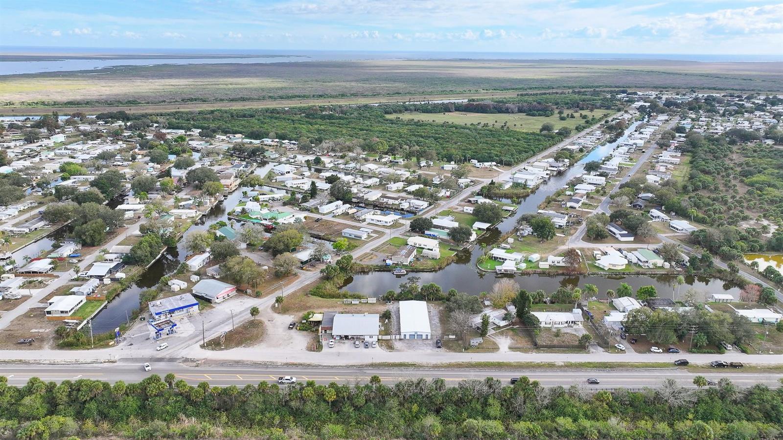 An aerial view shows a residential community with canals, mobile homes, and a main road — 1110 Buckhead Ridge Road, Okeechobee FL 34974, OKEECHOBEE, FL