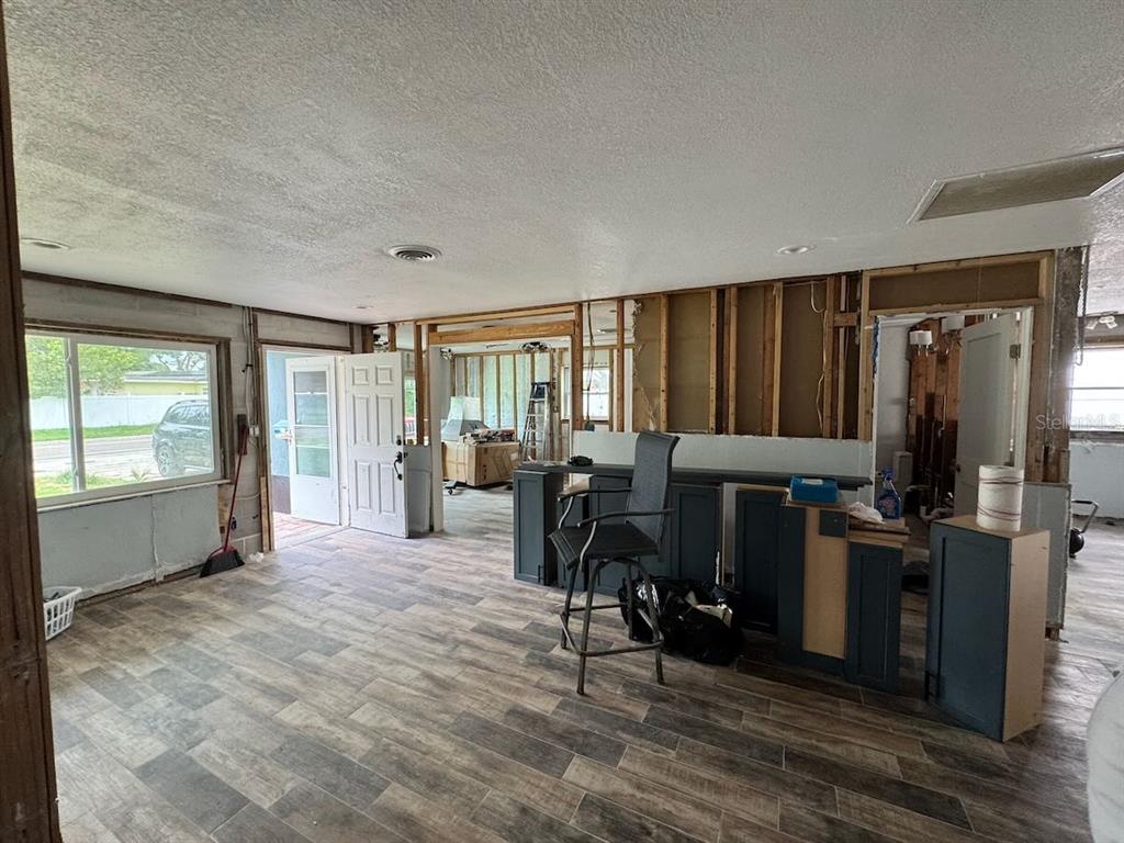 An interior room under renovation features exposed wall studs, dark blue base cabinets, and wood-look flooring — 5451 BAYOU GRANDE BOULEVARD NE, ST PETERSBURG, FL
