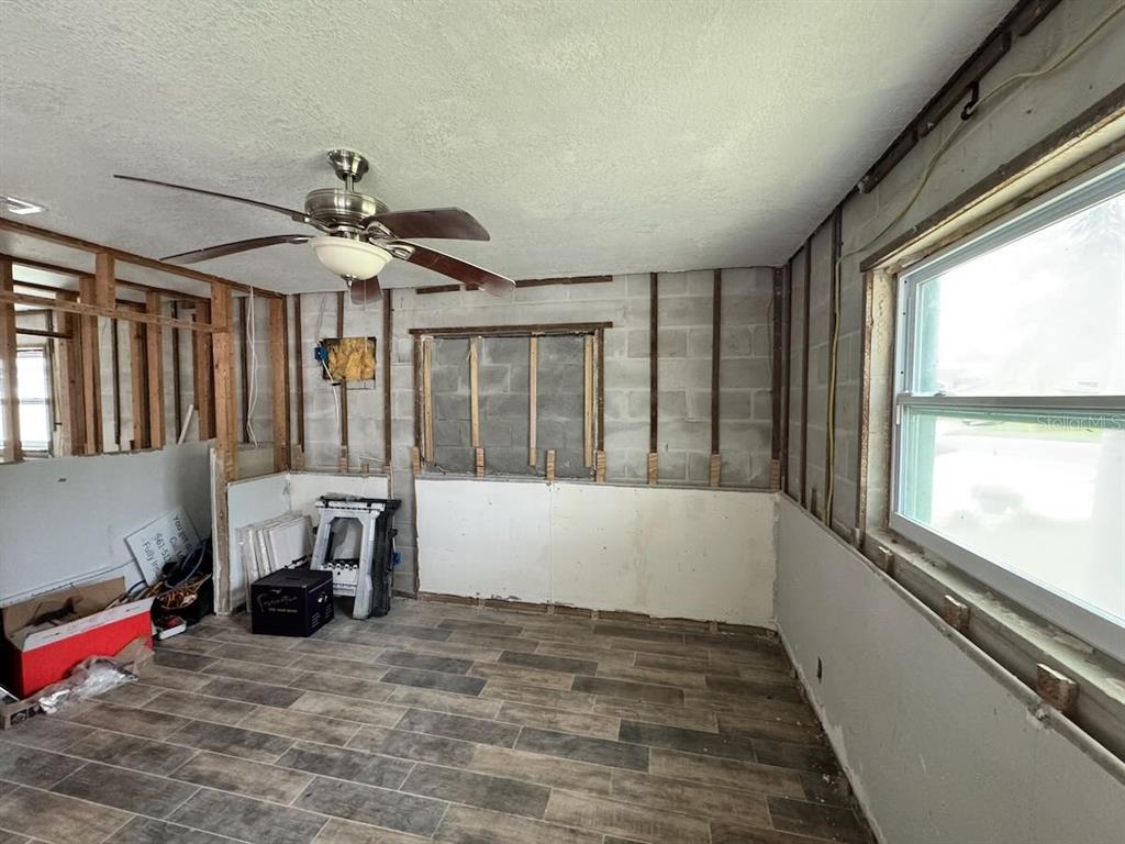 An unfinished room features exposed concrete block walls, wood furring strips, and wood-look tile flooring — 5451 BAYOU GRANDE BOULEVARD NE, ST PETERSBURG, FL