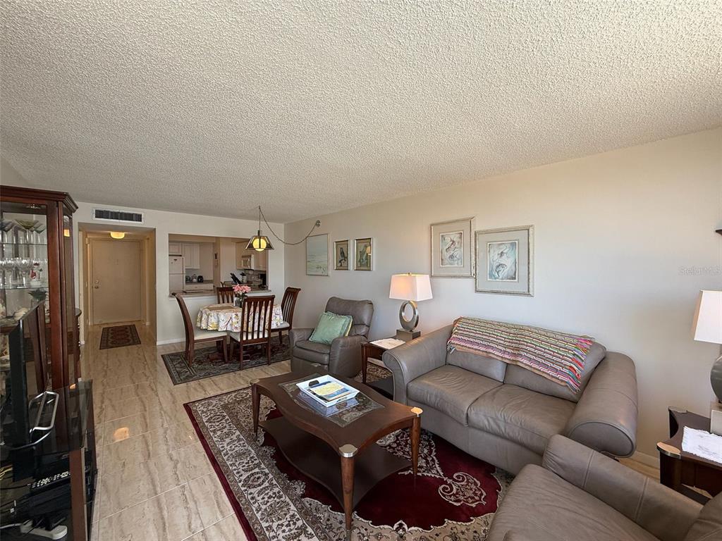 A living room and dining area feature tile flooring, a leather sofa, and area rugs — 6279 SUN BOULEVARD UNIT 403, ST PETERSBURG, FL