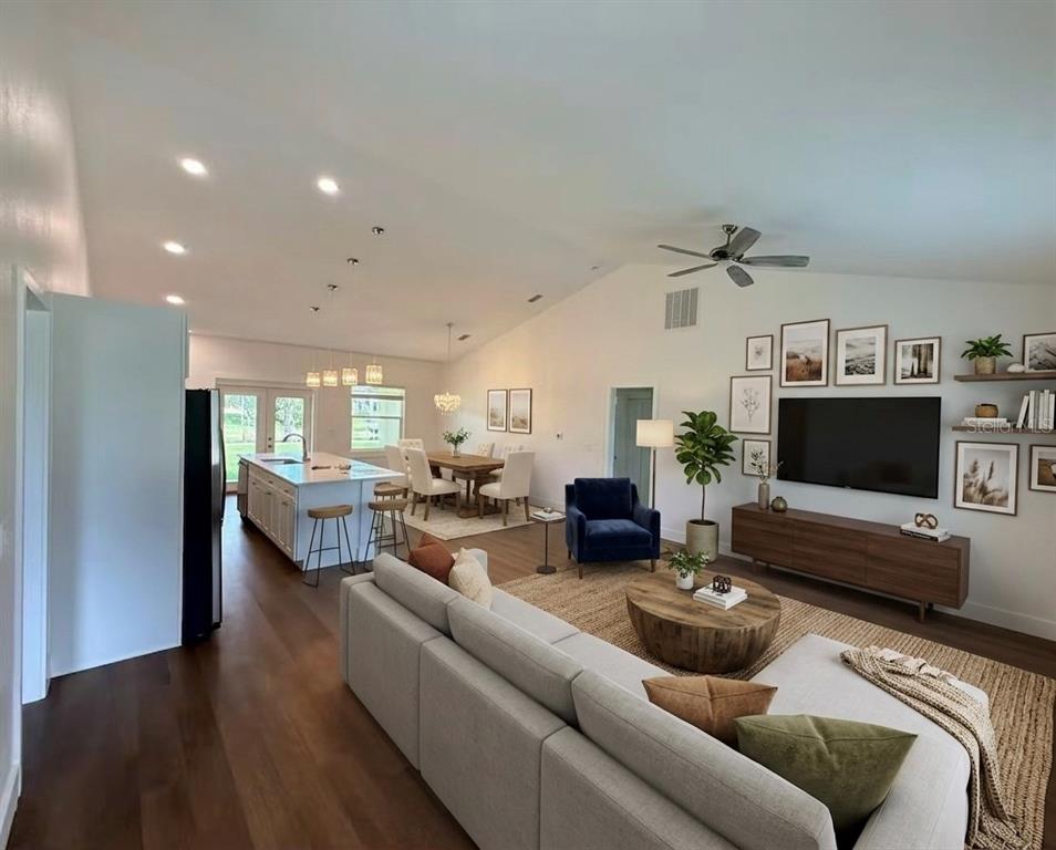 An open-concept living and dining area features a kitchen island, hardwood floors, and vaulted ceilings — 99 BICKFORD DRIVE, PALM COAST, FL