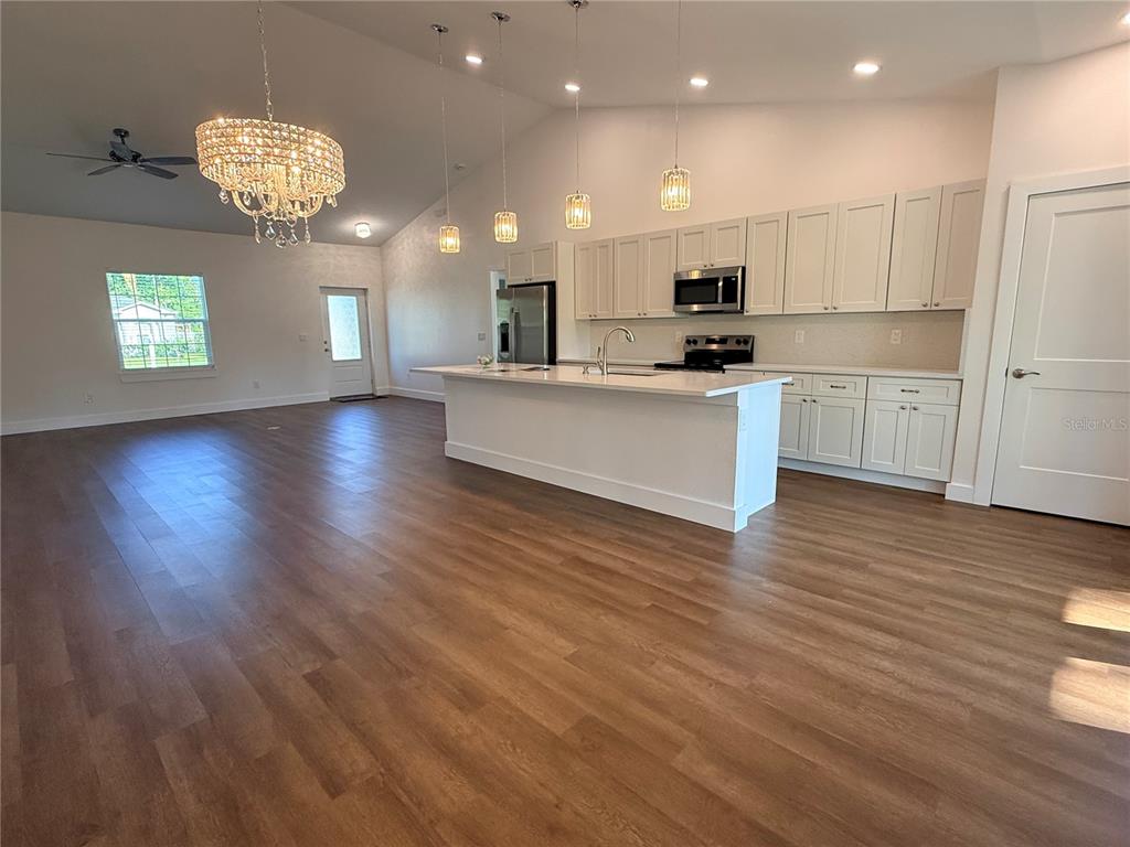 A kitchen with white cabinets, a central island, and wood-look flooring in an open space — 99 BICKFORD DRIVE, PALM COAST, FL