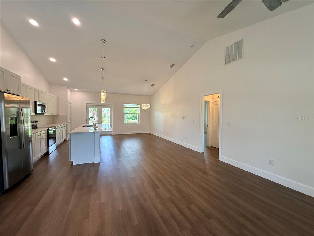 A kitchen with white cabinets and an island opens into a large living area — 99 BICKFORD DRIVE, PALM COAST, FL