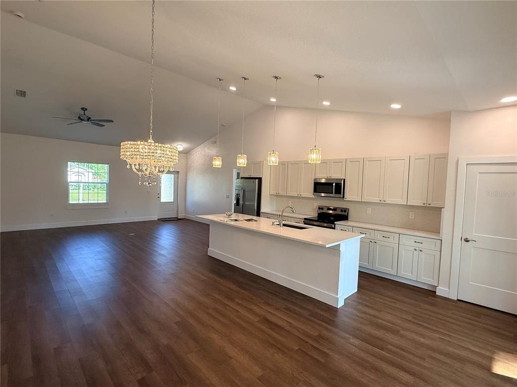 A kitchen with white cabinets and a large island opens into a spacious living area — 99 BICKFORD DRIVE, PALM COAST, FL