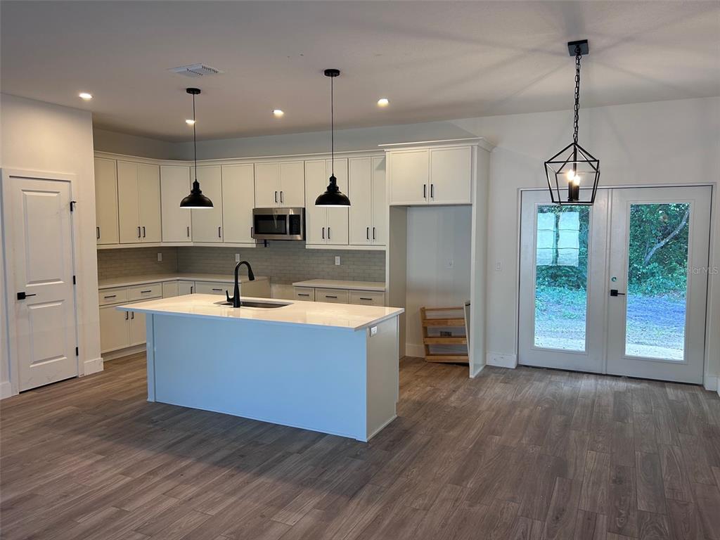 A modern kitchen features white cabinetry, a central island with a sink, and pendant lighting — 340 KIMBLE AVENUE, OVIEDO, FL